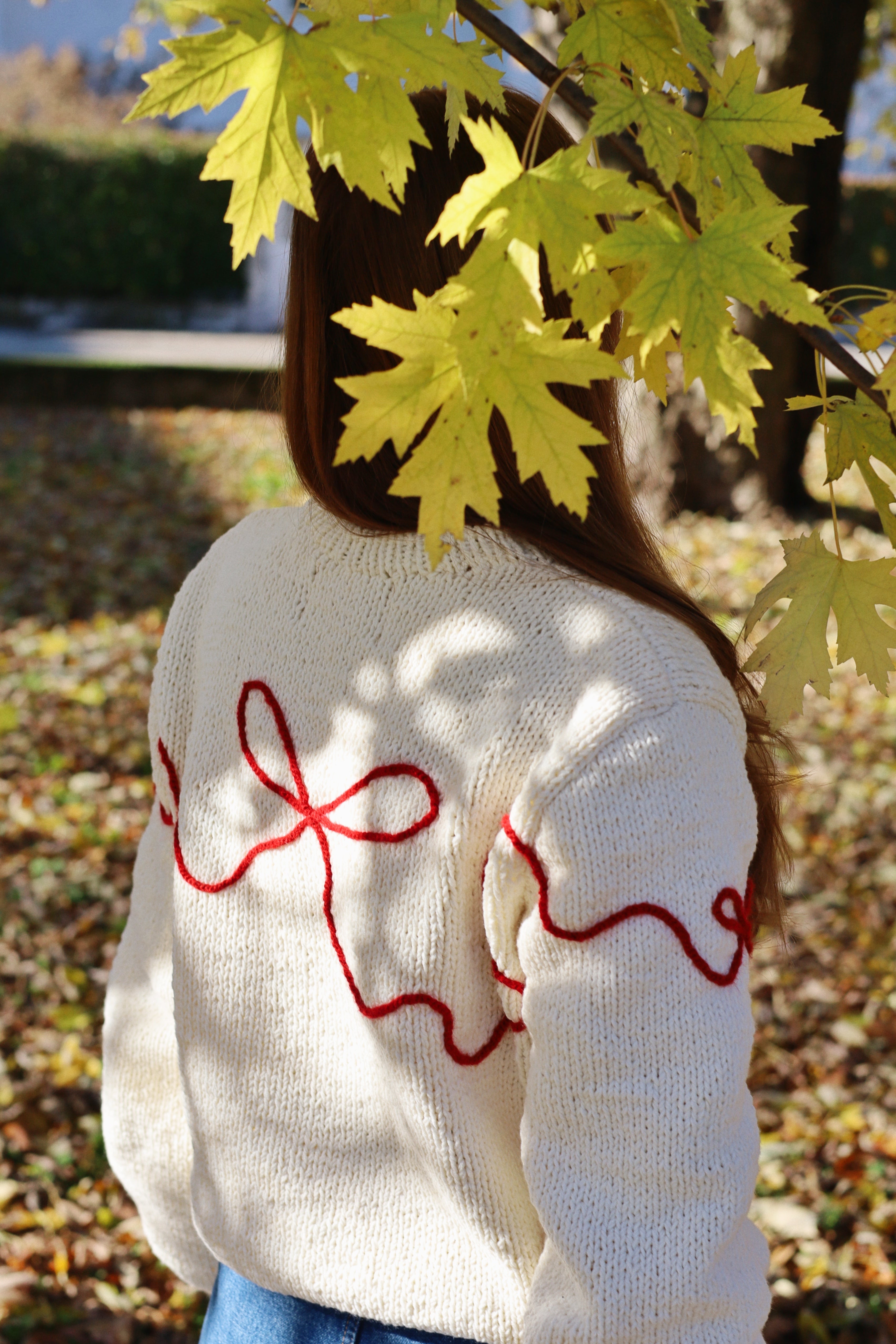 Beige hand knitted sweater with embroidered red bows and three bears.