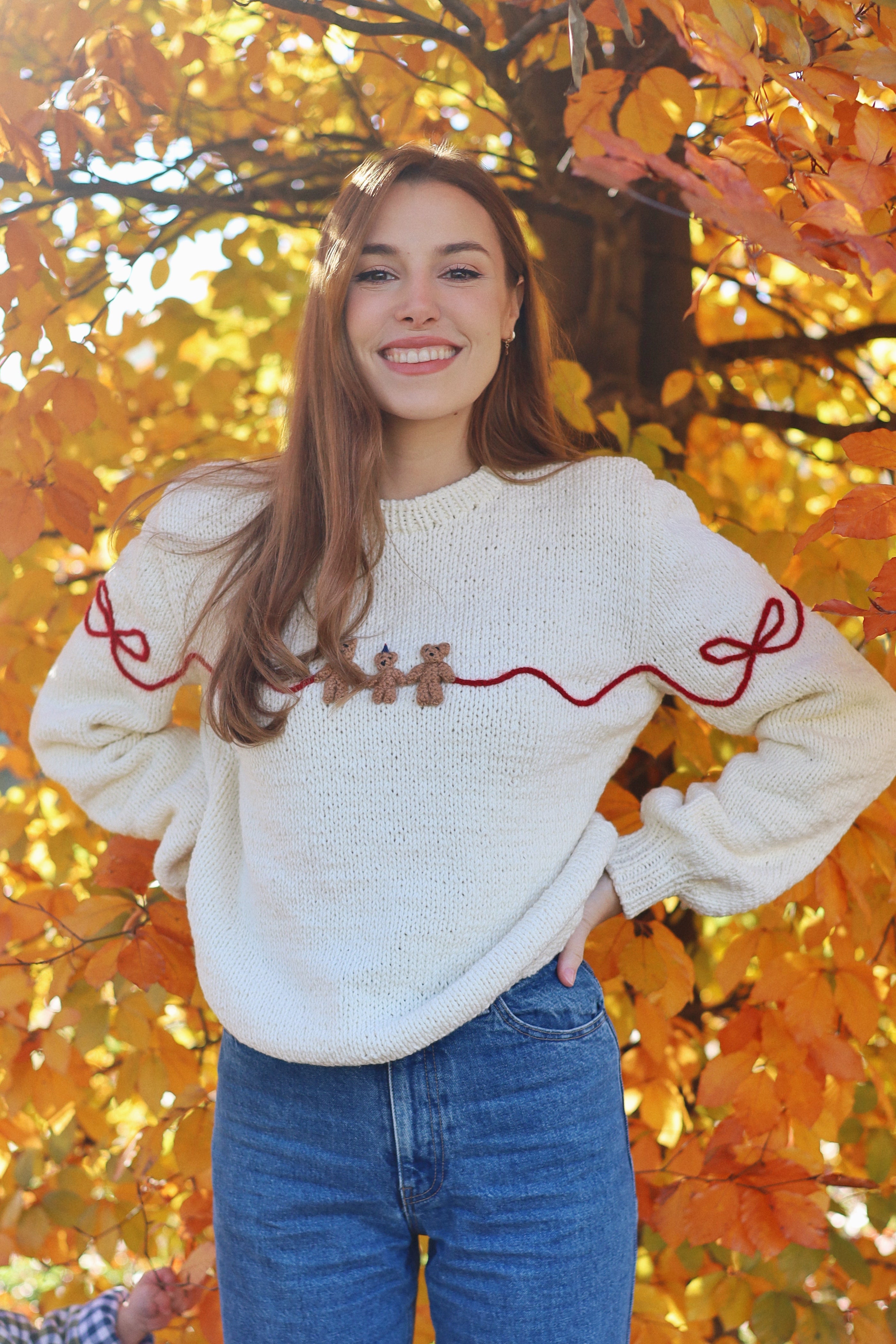 Beige hand knitted sweater with embroidered red bows and three bears.