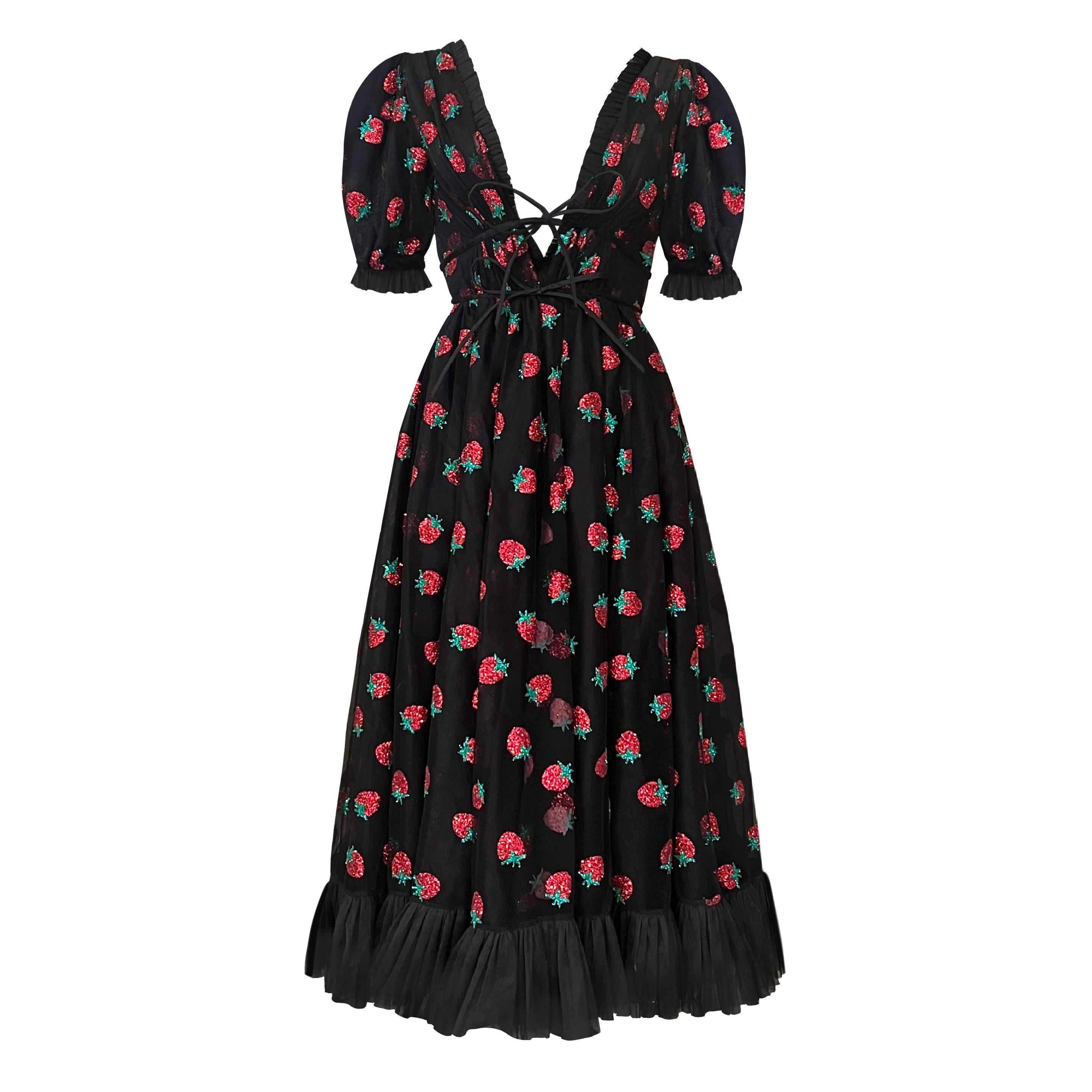 A midi dress with a black base covered in glittery strawberries. The dress features a tie up detail and puffy sleeves.