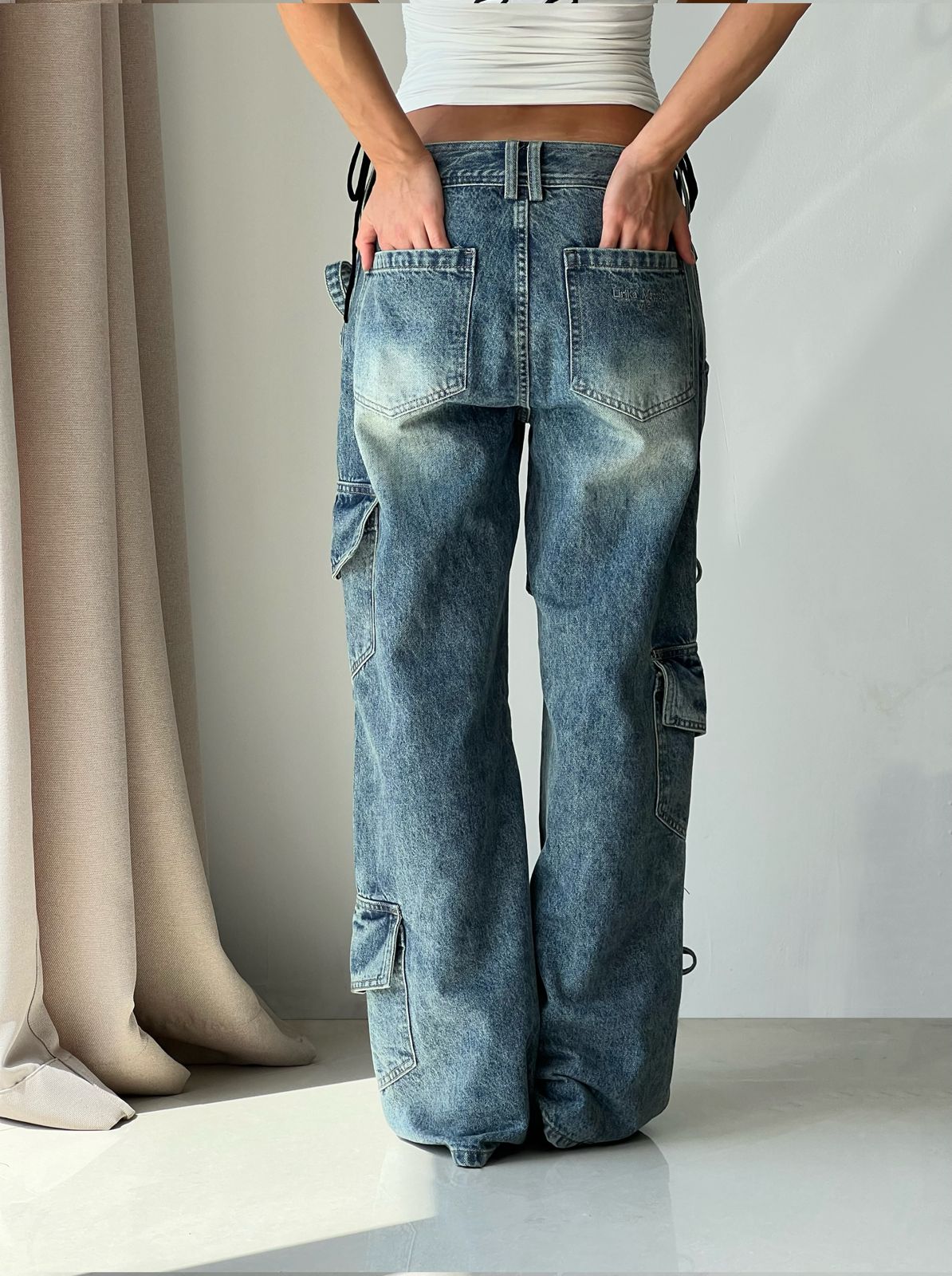 Blue denim jeans with tie details on a white background