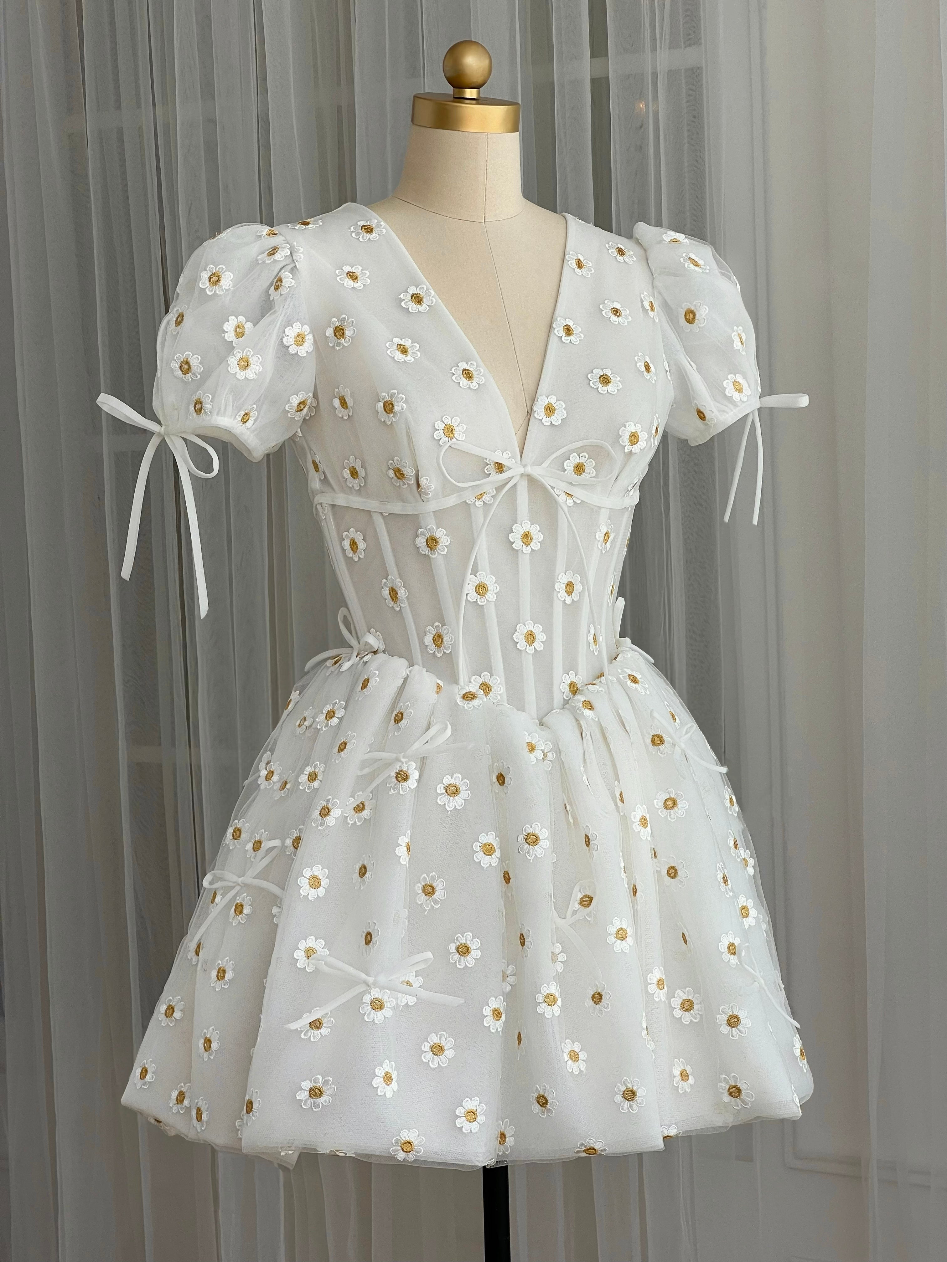 White mini dress with embroidered daisies, v-neck and short sleeves