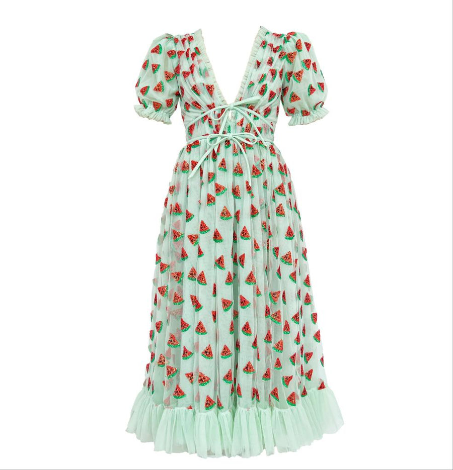 A midi dress with a green background and a pattern of red watermelon slices. The dress features puffy sleeves and a tie-up detail at the front.
