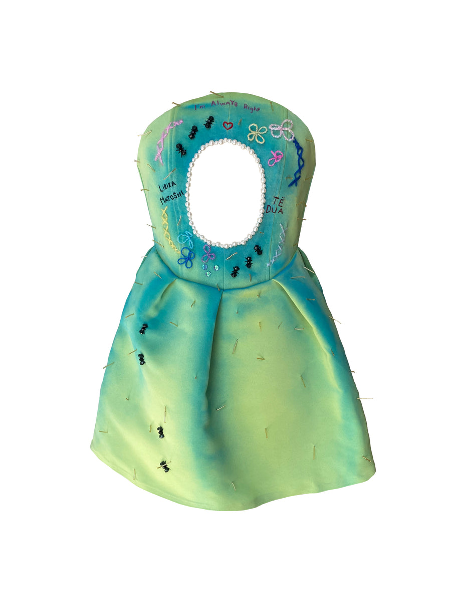 A green satin dress with a holographic pattern and embellishments, displayed on a mannequin.
